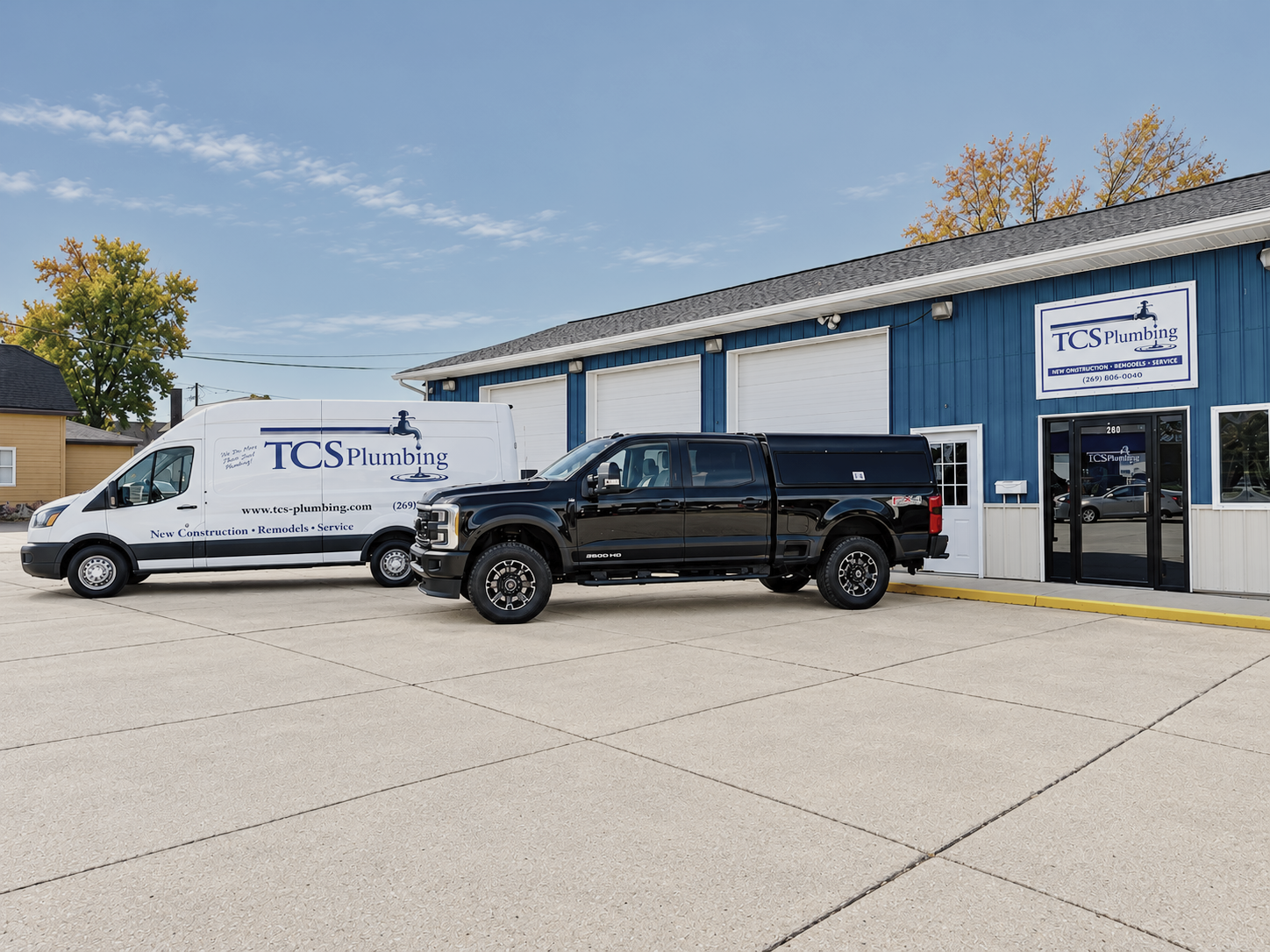 Commercial building with a white van and black pickup parked outside under a blue sky
