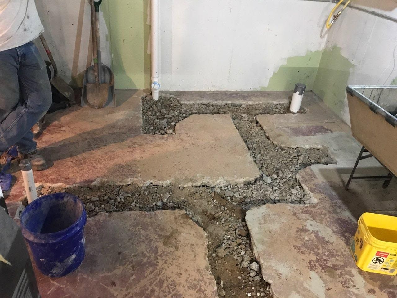 Partially poured concrete floor with gravel trenches in a workshop area