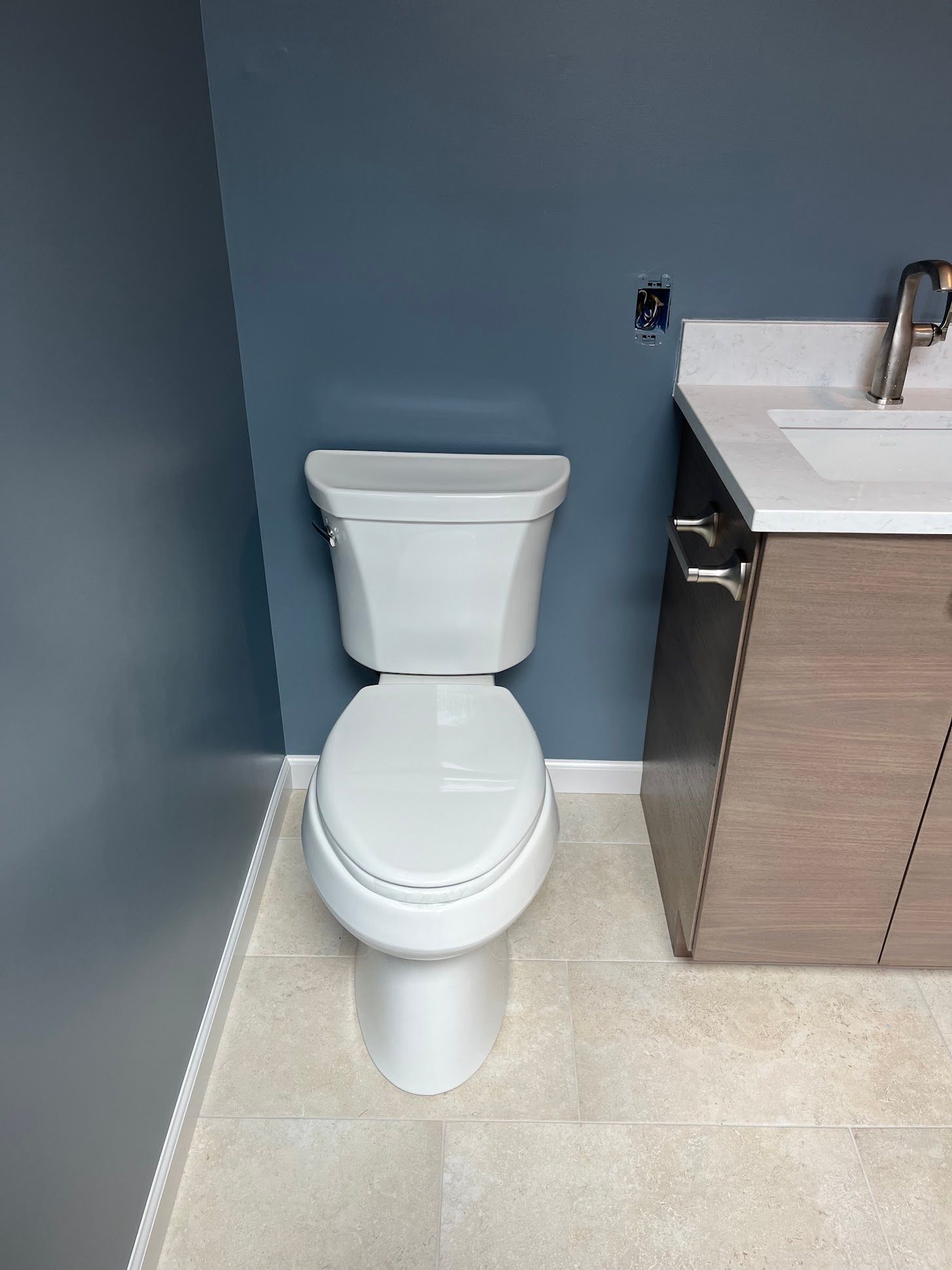 Water heater in a basement utility area with exposed pipes, wiring, and nearby storage items.