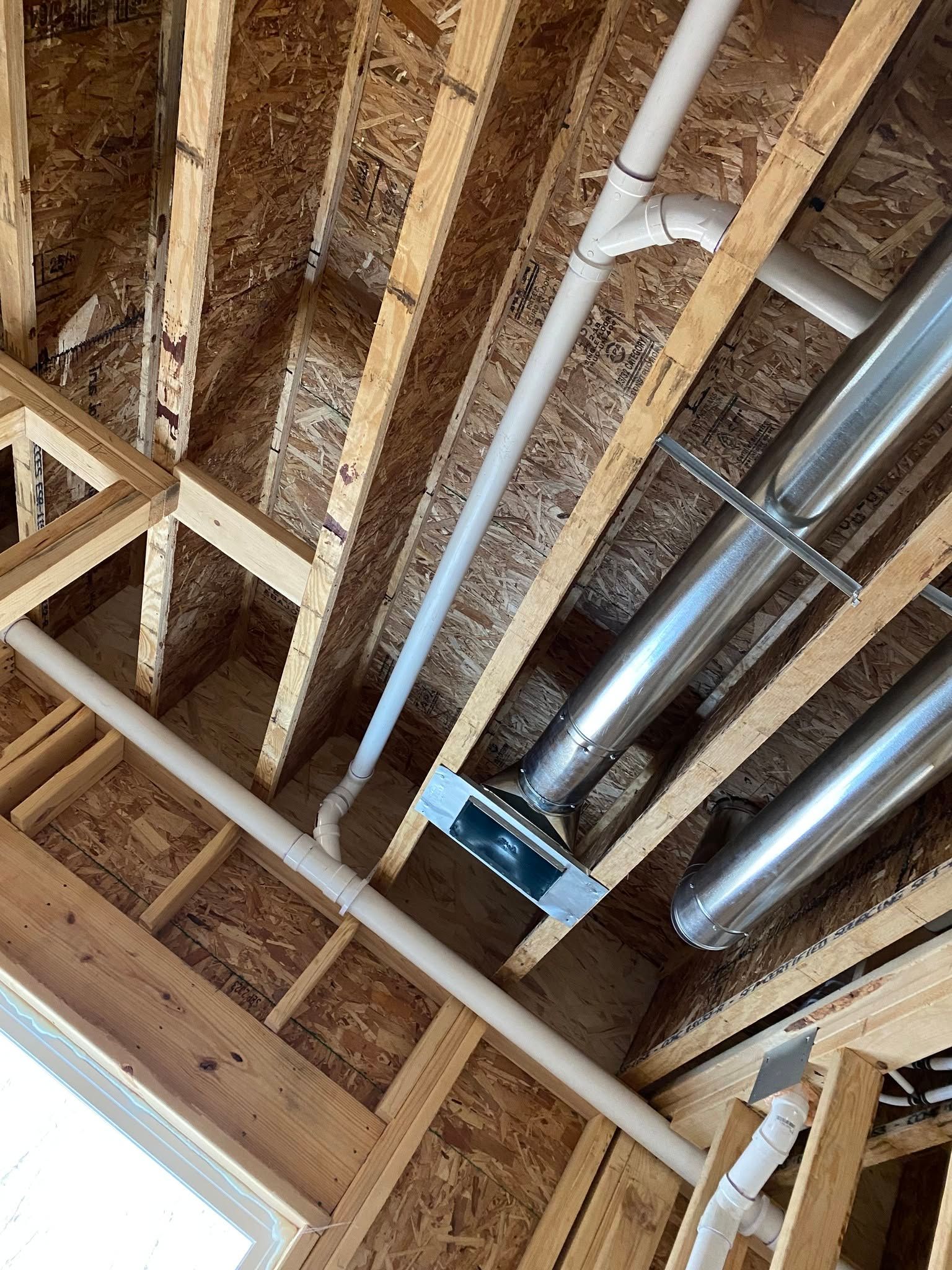 Exposed ceiling framing with ducts and pipes in an unfinished room
