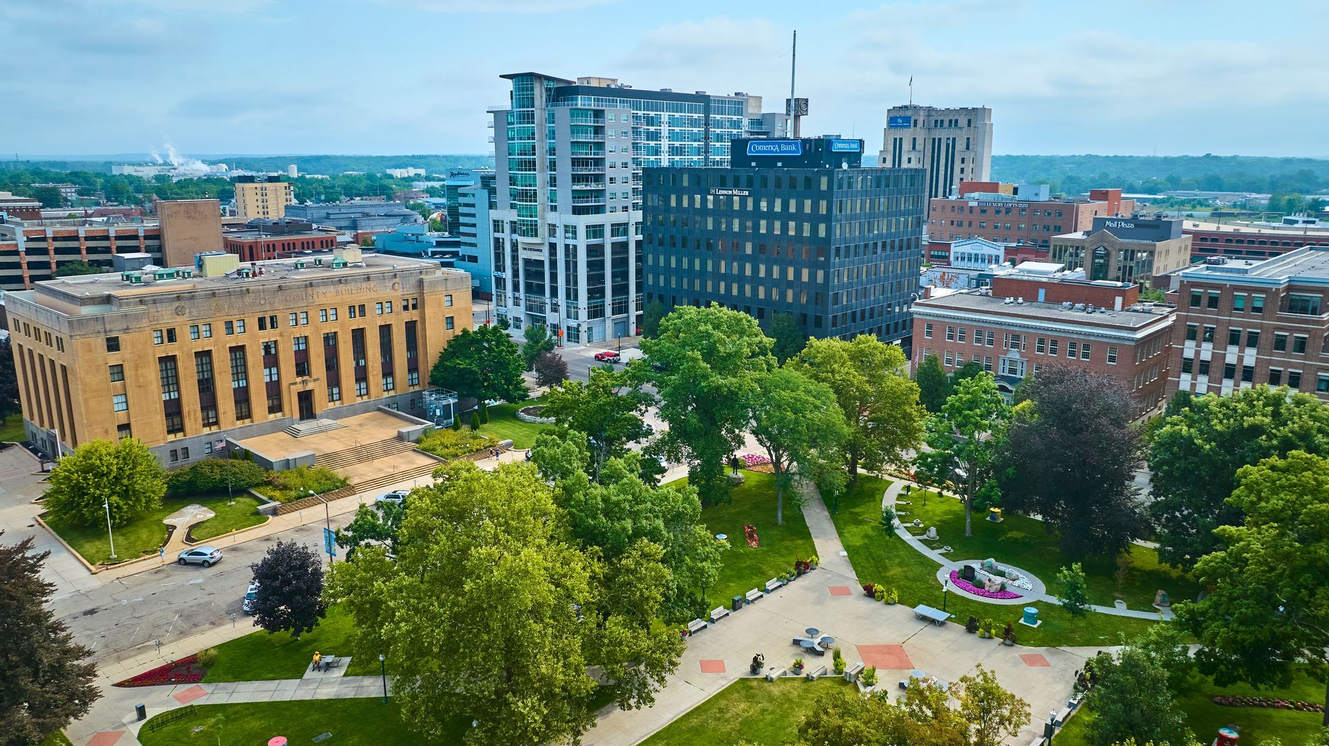 Aerial view of Bronson Park in Kalamazoo, MI with trees, paths, and modern office buildings nearby