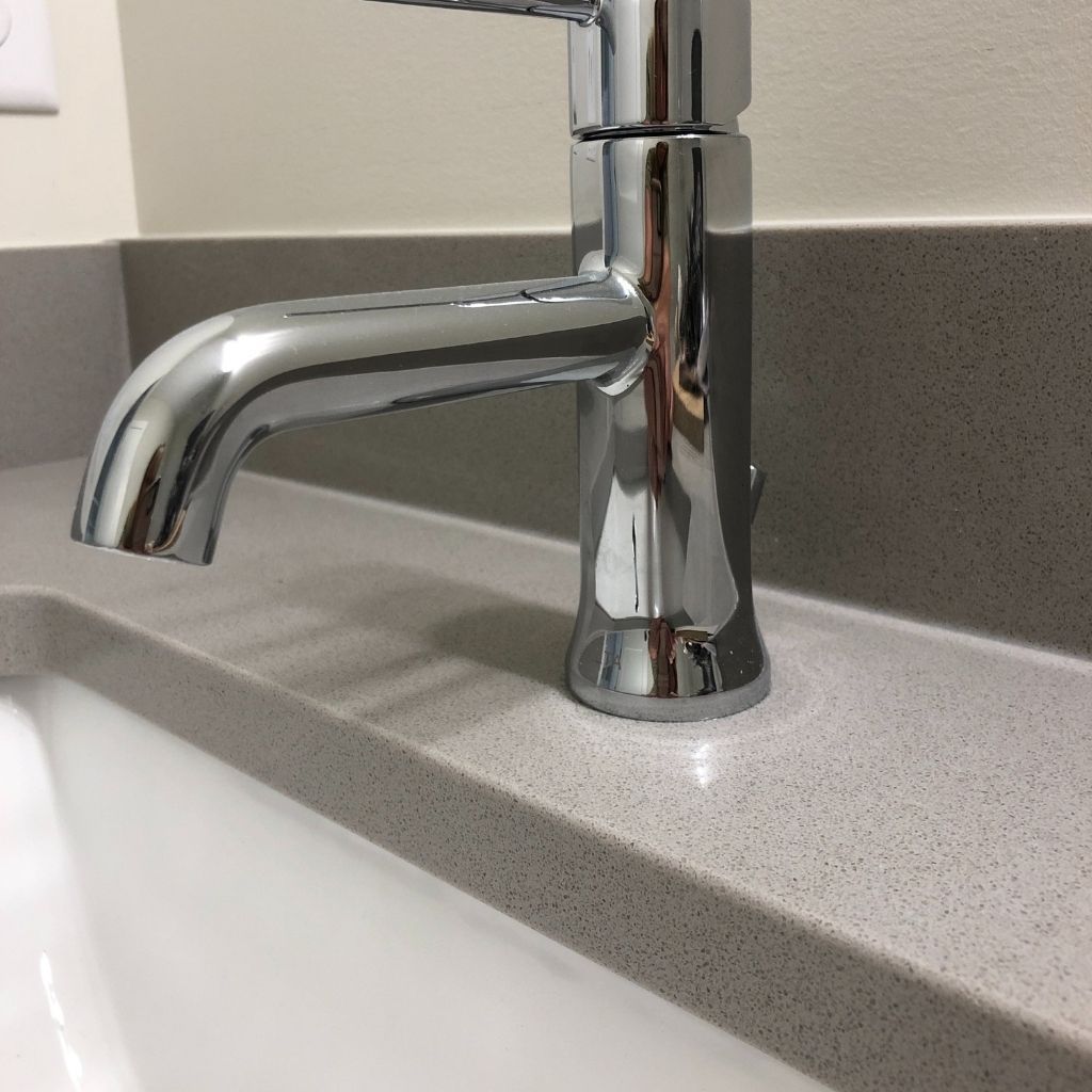 Chrome bathroom sink faucet on a speckled countertop