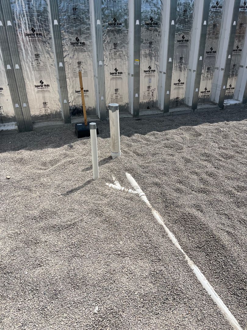 White signpost in dry gravel yard beside a weathered metal fence.