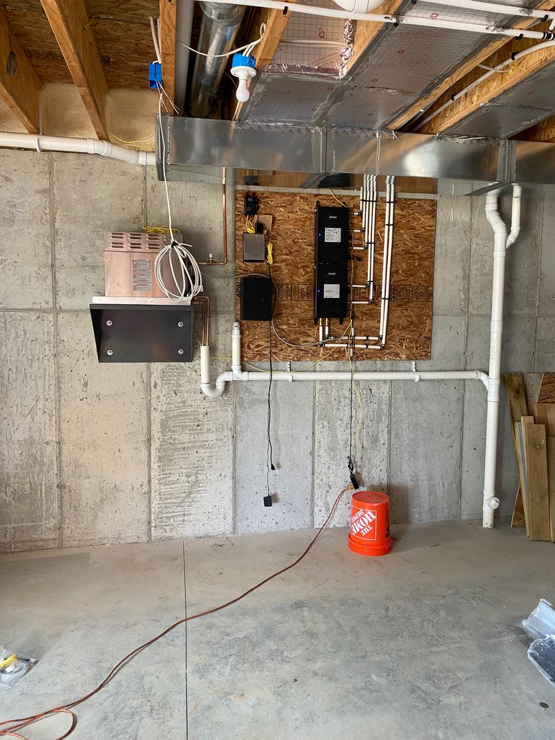 Unfinished basement with exposed joists, electrical panel, concrete walls, and a red bucket on the floor
