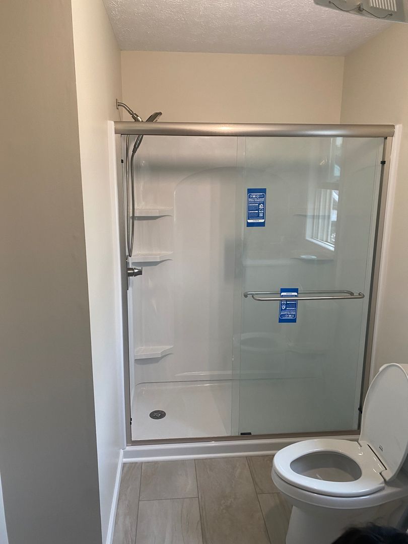 Bathroom with a walk-in shower, toilet, and beige walls.