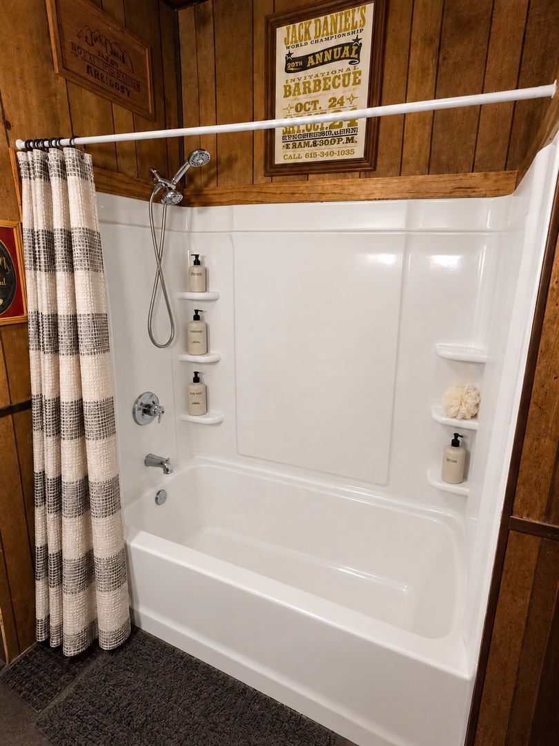 Bathroom tub with white shower walls, curtain, hanging caddies, and a grab bar in a wood-paneled room