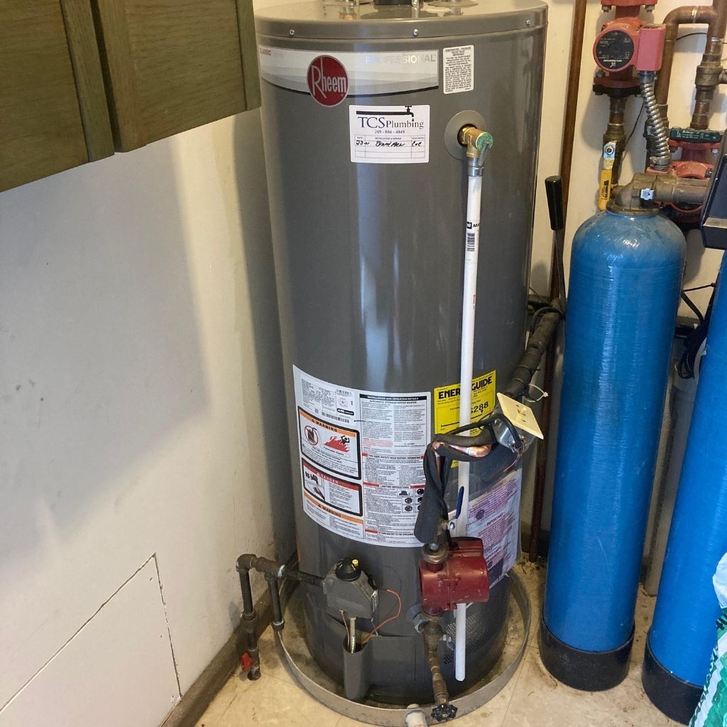 Water heater with pipes and blue water softener tanks in a utility room