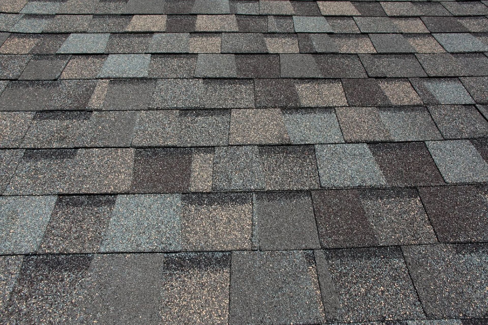Close-up of gray and brown asphalt roof shingles in a repeating pattern