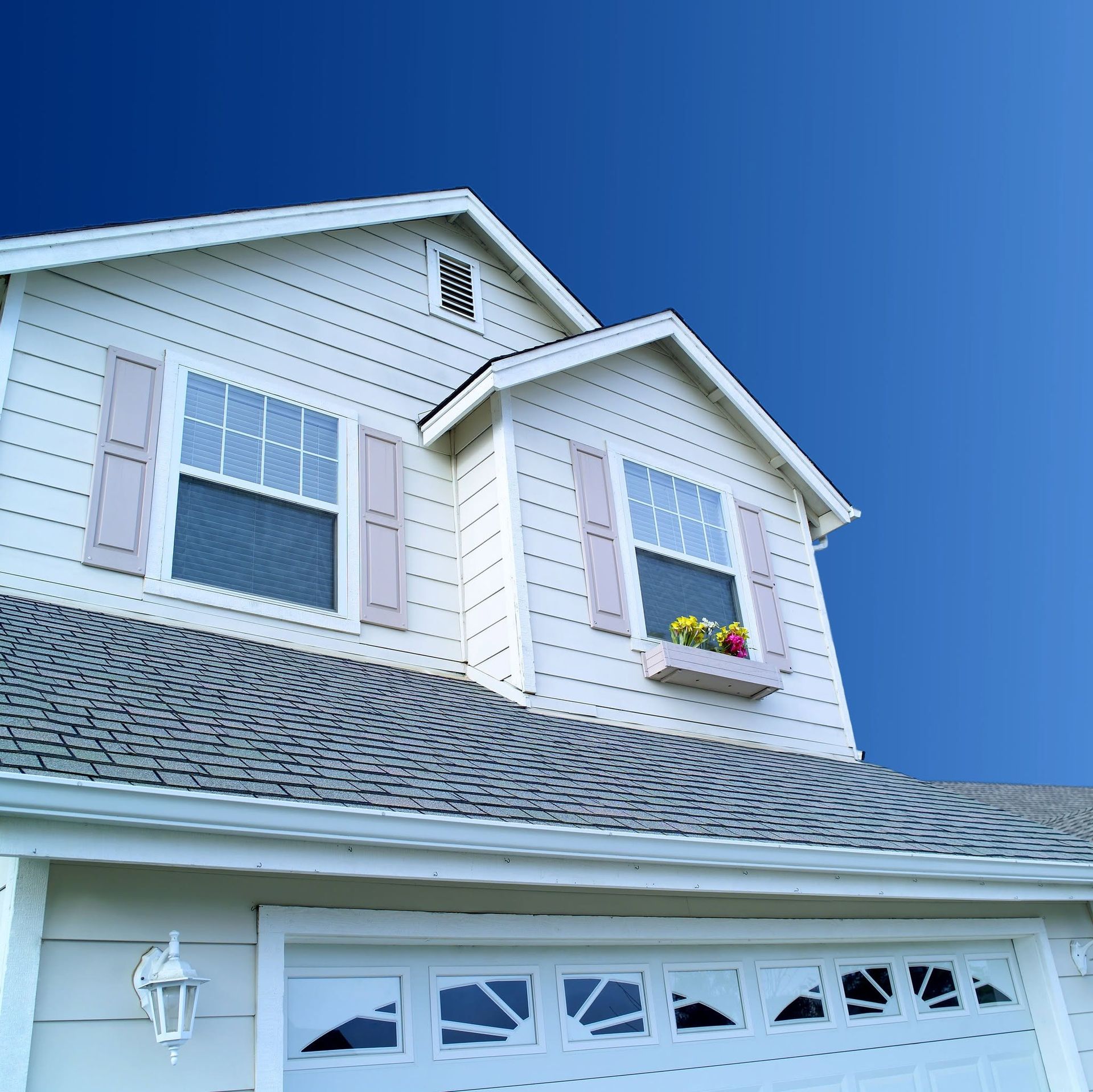 White house exterior with blue shutters, gray roof, and blue sky