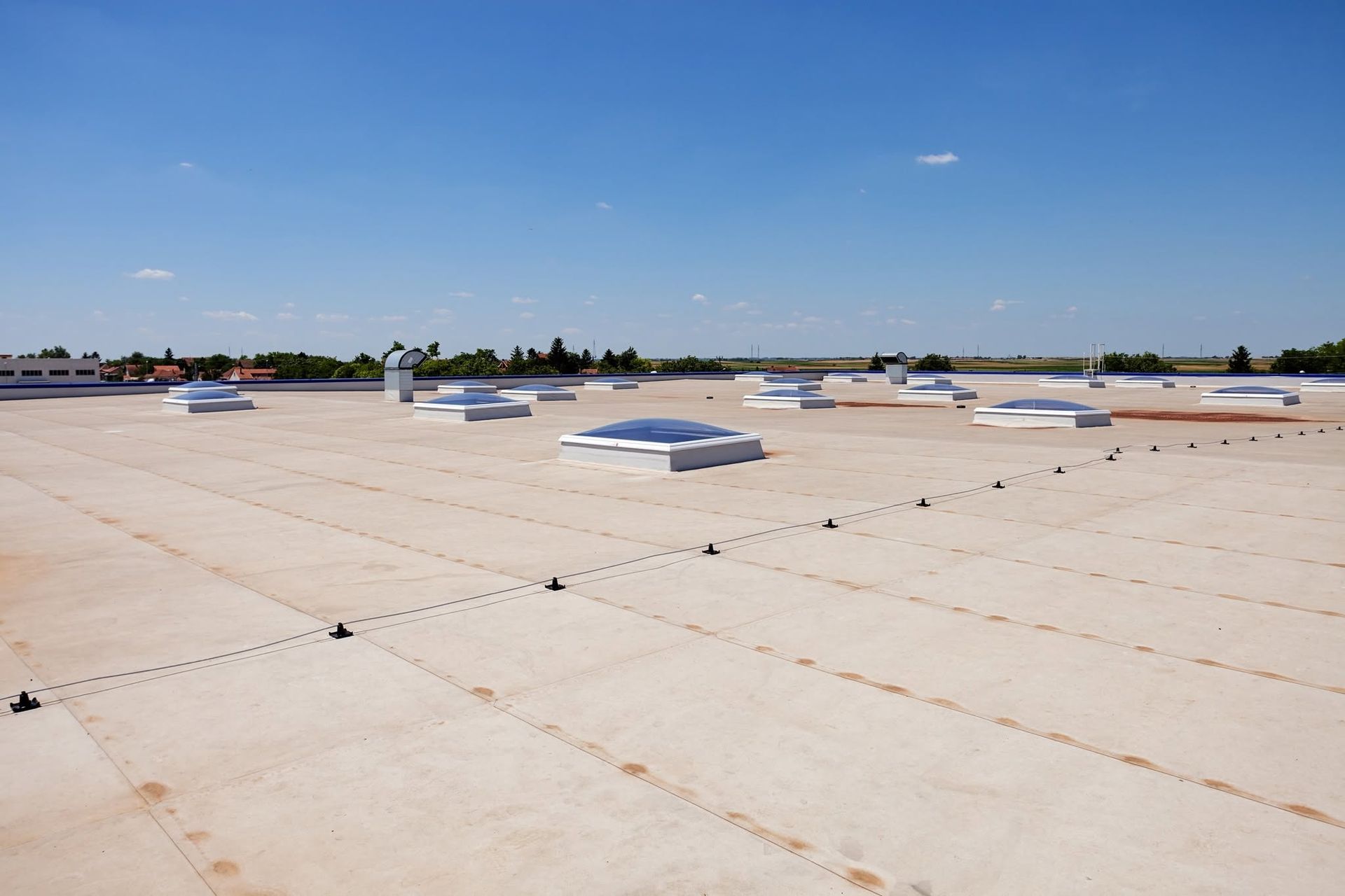 Flat white rooftop with several skylights under a clear blue sky