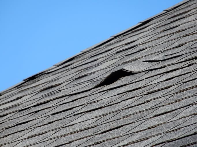 Roof shingles with a small raised vent against a blue sky