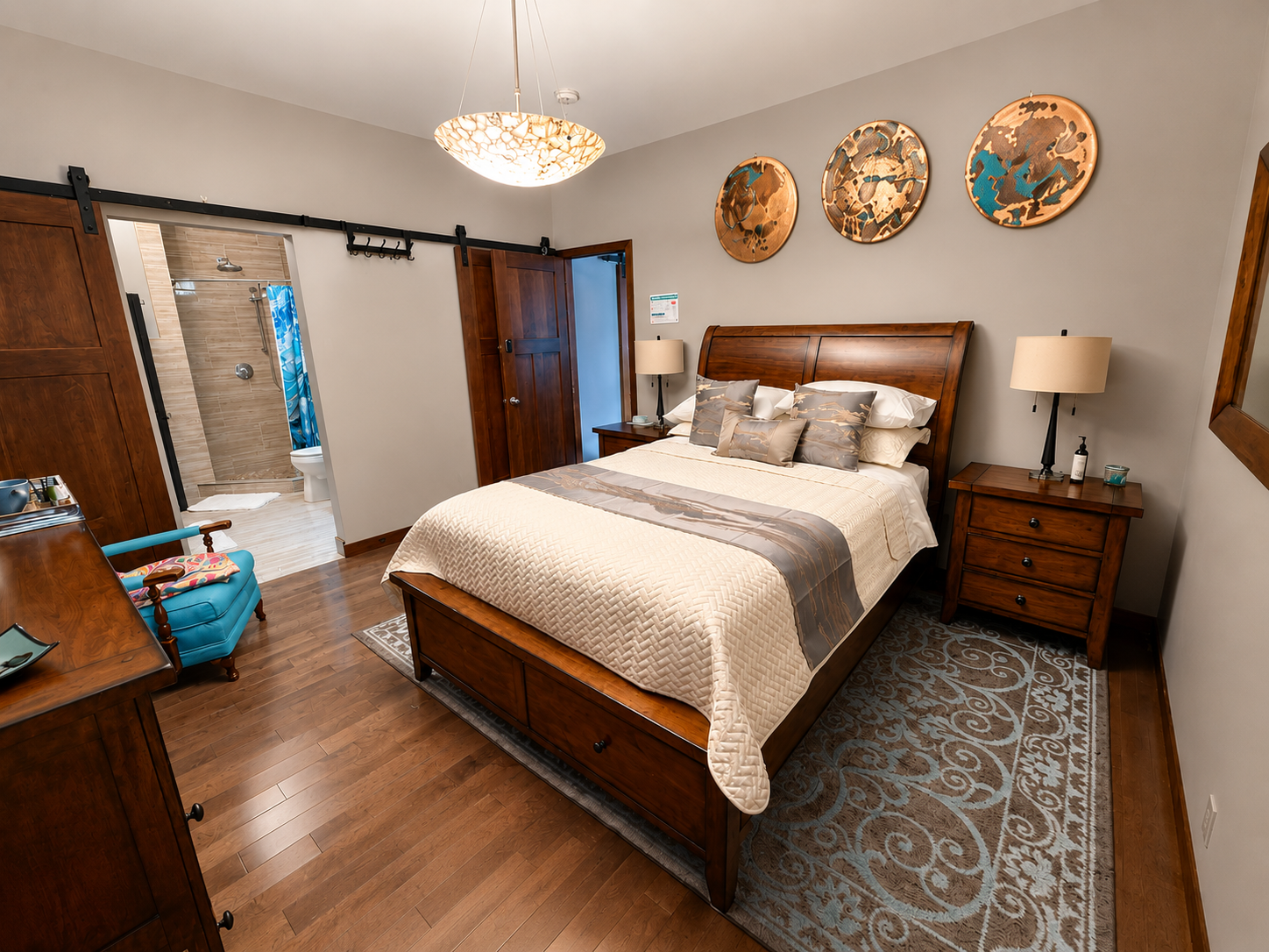Spacious bedroom with a wood bed, patterned rug, nightstands, and sliding barn doors.