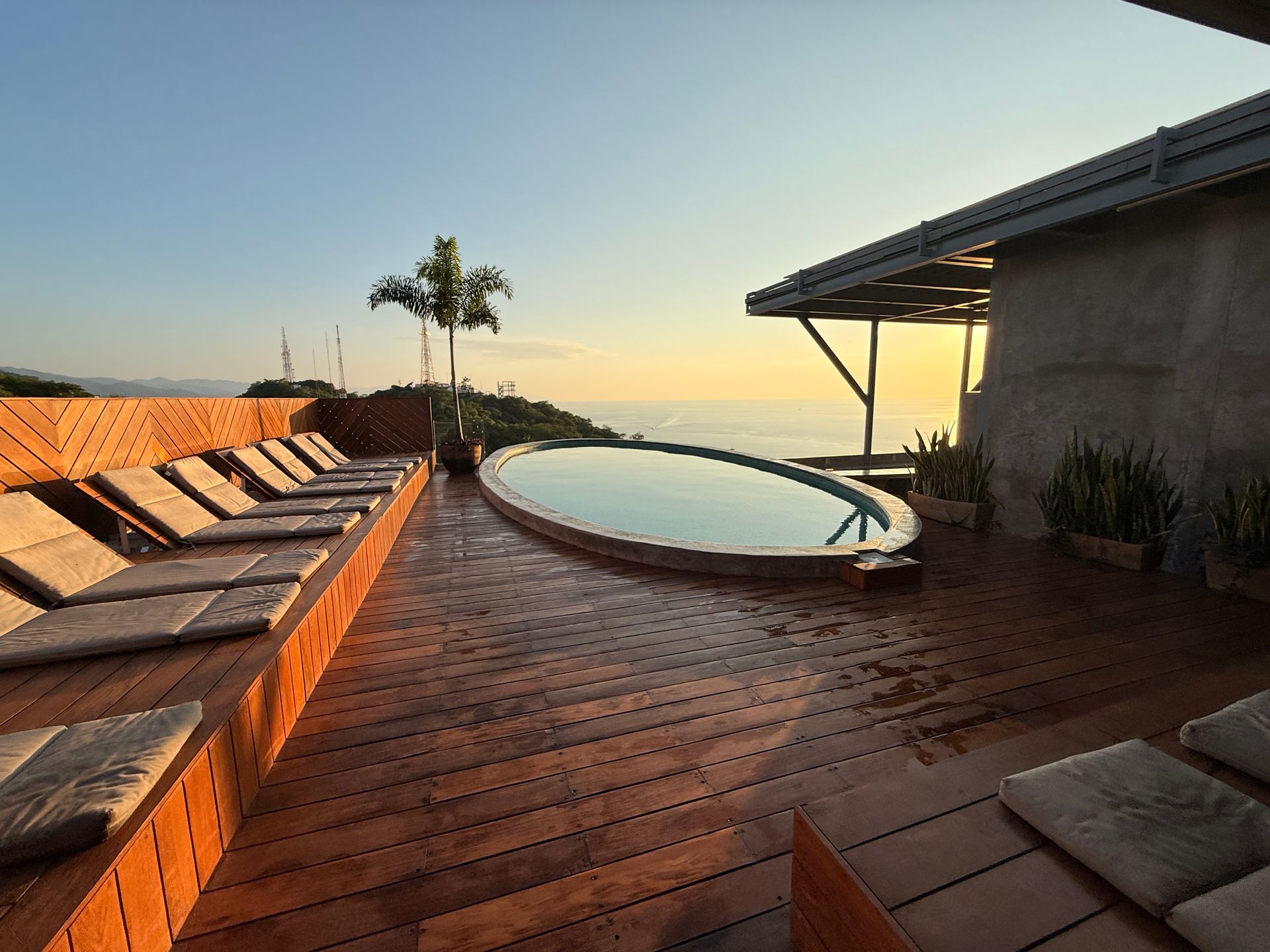 Infinity pool on a wooden deck overlooking the ocean under a bright blue sky
