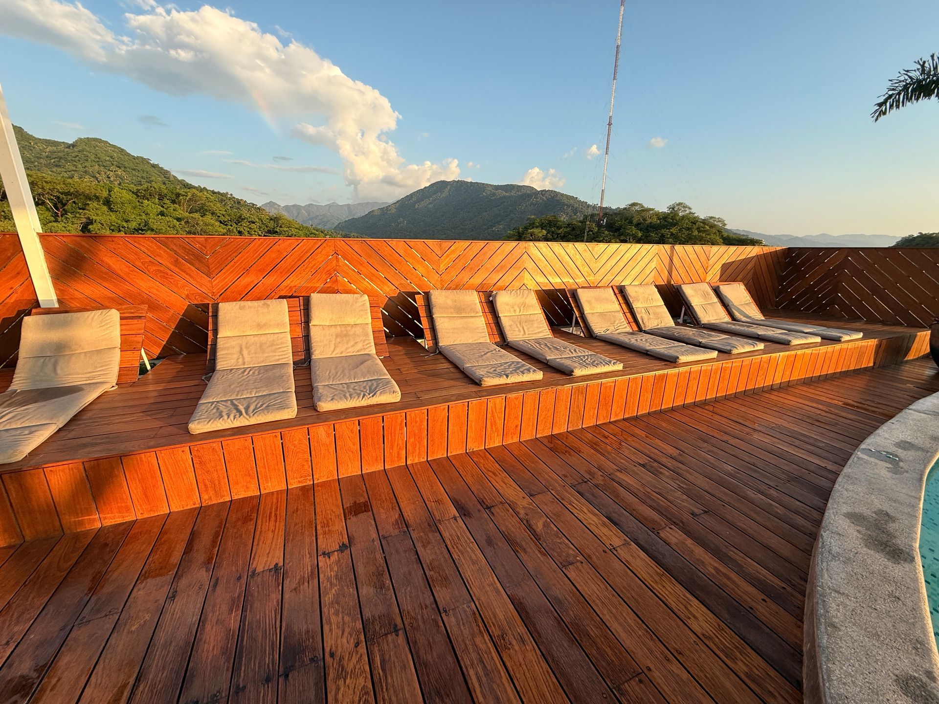 Wooden sun deck with white lounge chairs, potted plants, and a shaded outdoor seating area