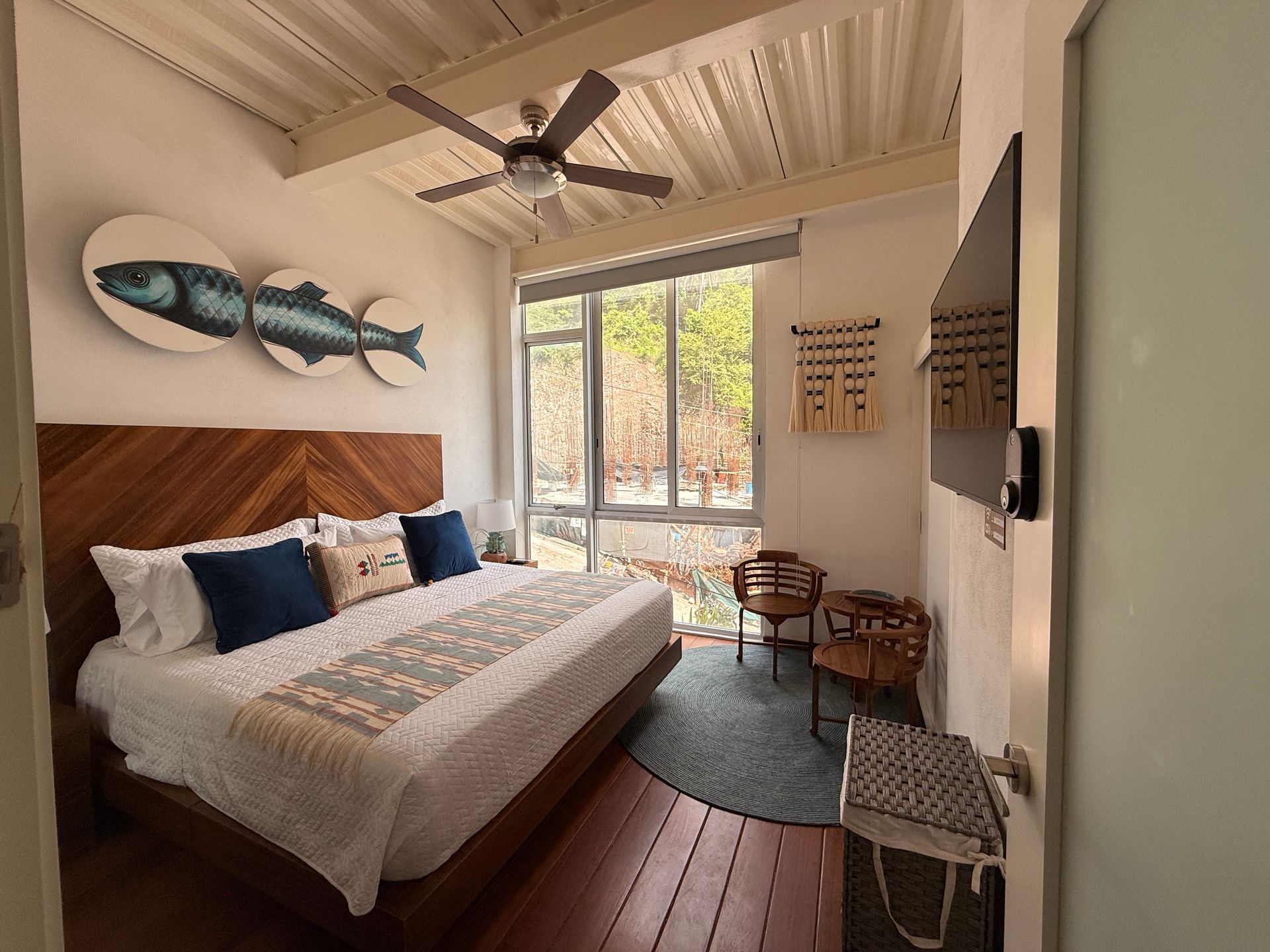 Cozy bedroom with wooden bed, floral portrait above the headboard, and warm sunlight through open windows