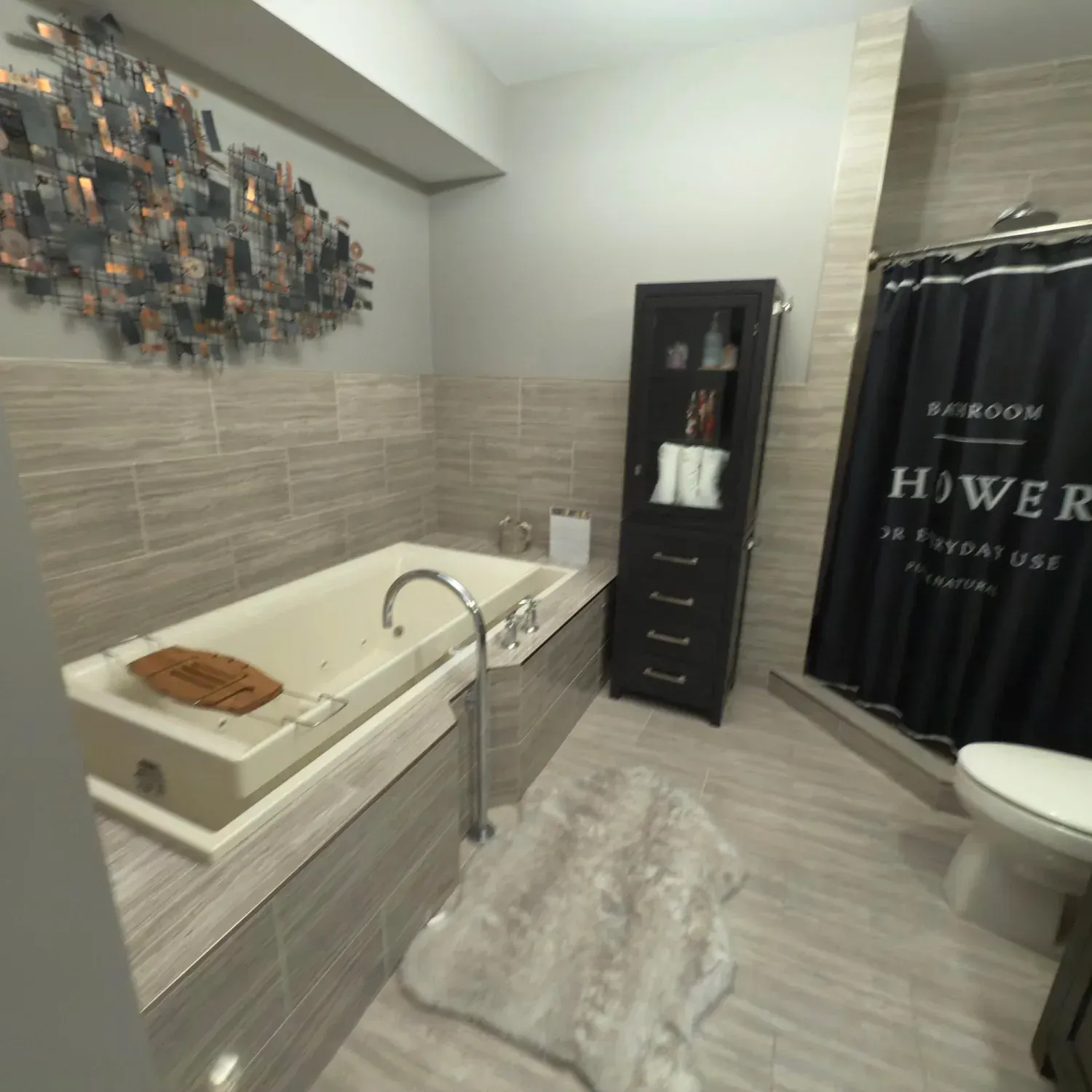 Modern bathroom with a bathtub, shower curtain, vanity cabinet, and gray tile flooring