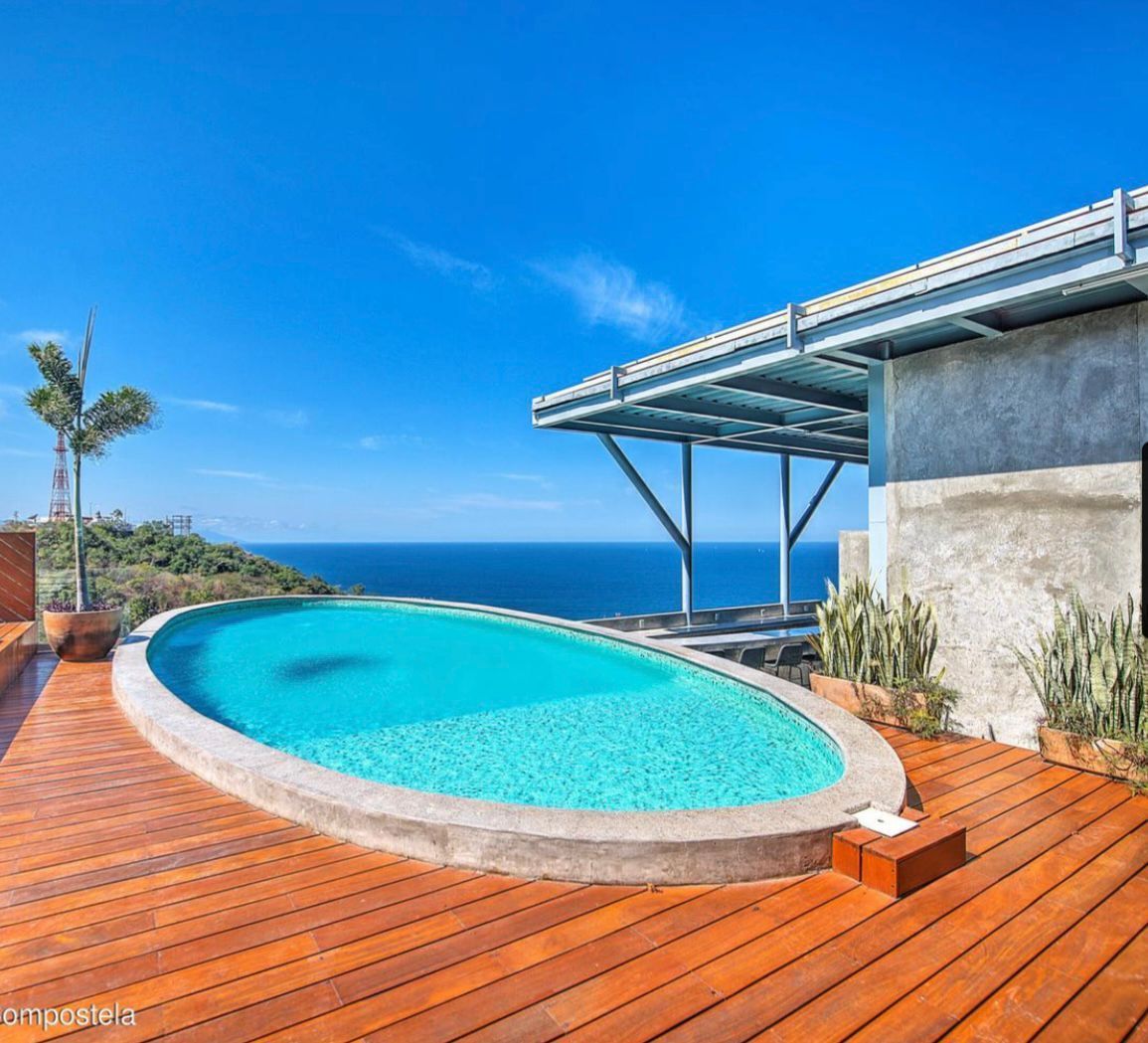 Infinity pool on a wooden deck overlooking the ocean under a clear blue sky