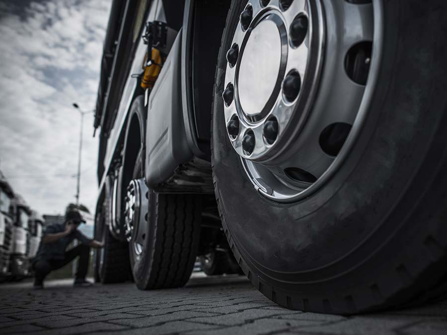 A man is kneeling down next to a large truck.
