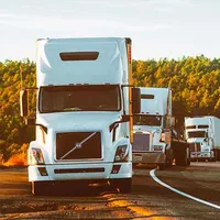 A row of semi trucks are driving down a highway.