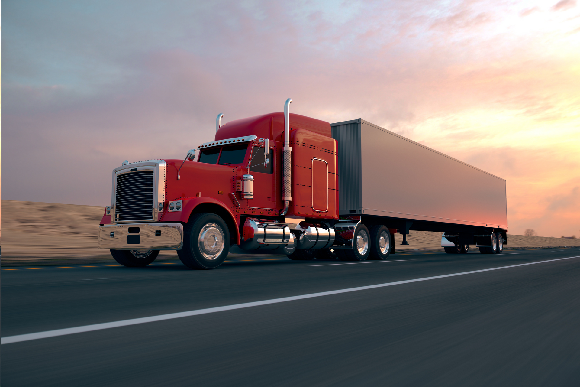 A red semi truck is driving down a highway at sunset.