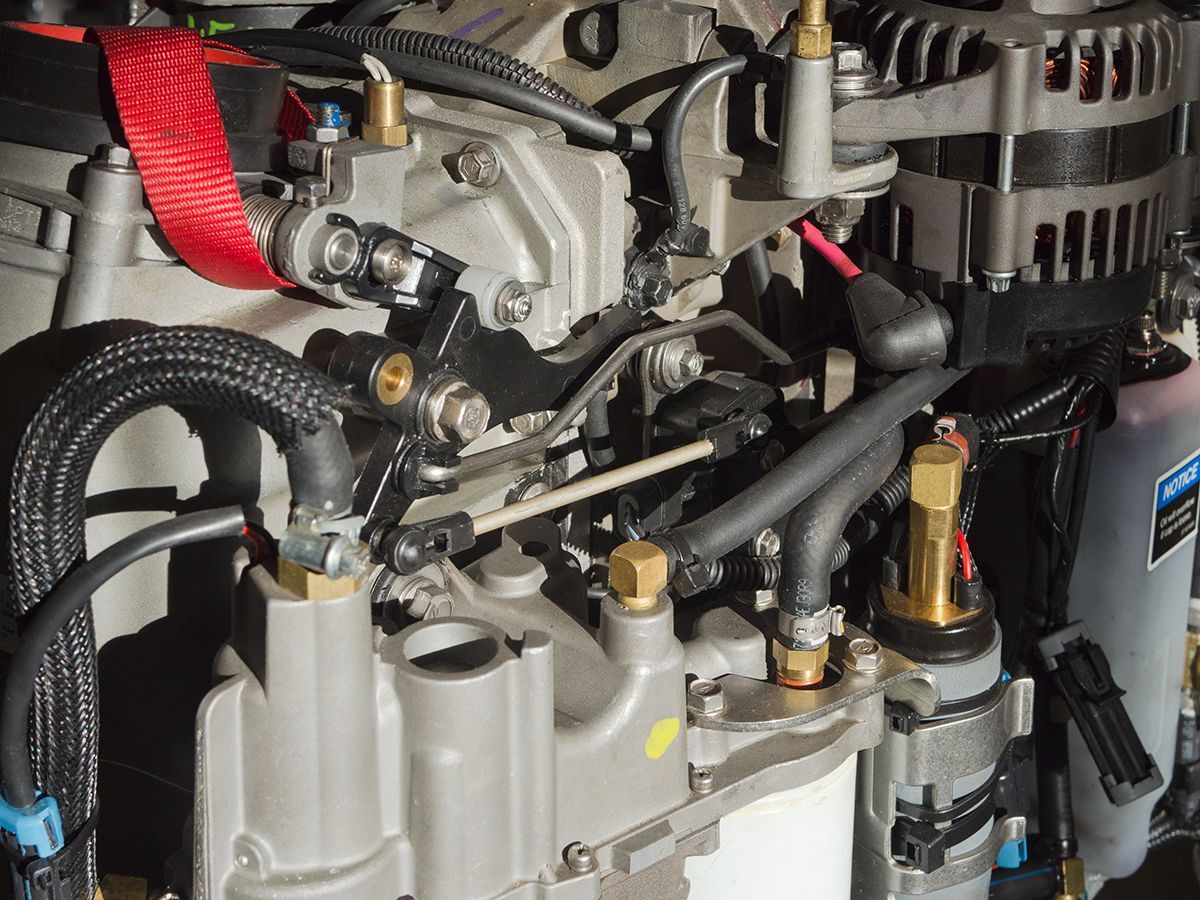 Close-up of a boat engine with various tubes, wires, and a red strap visible.