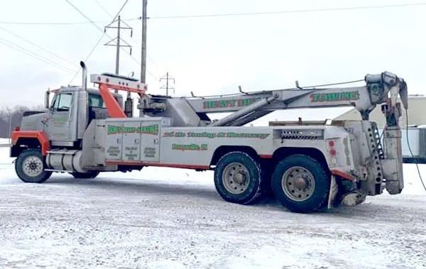 A large tow truck is parked in the snow.