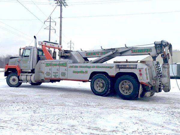 A large tow truck is parked in the snow.