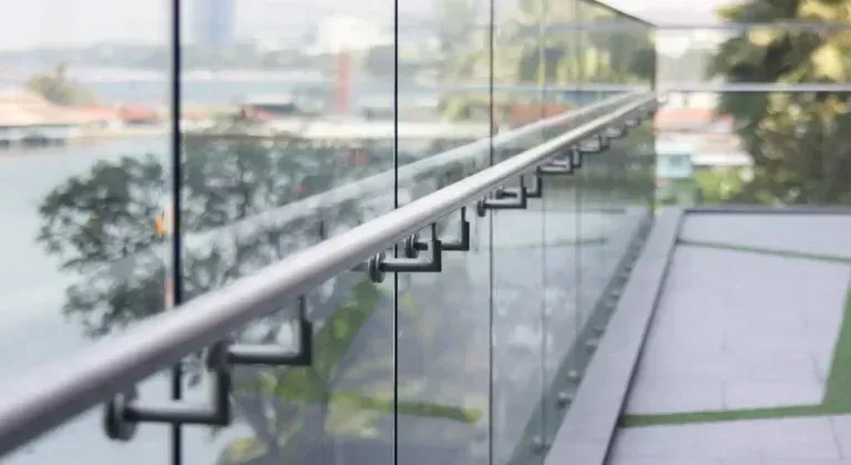 Glass balcony railing overlooking a blurred cityscape and water in daylight