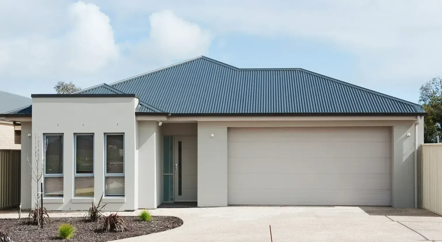 Modern single-story house with blue roof, light exterior, and attached garage