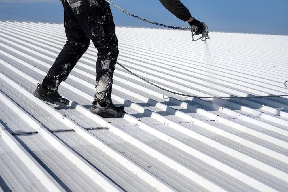 Worker installing metal roofing on a corrugated roof in bright sunlight