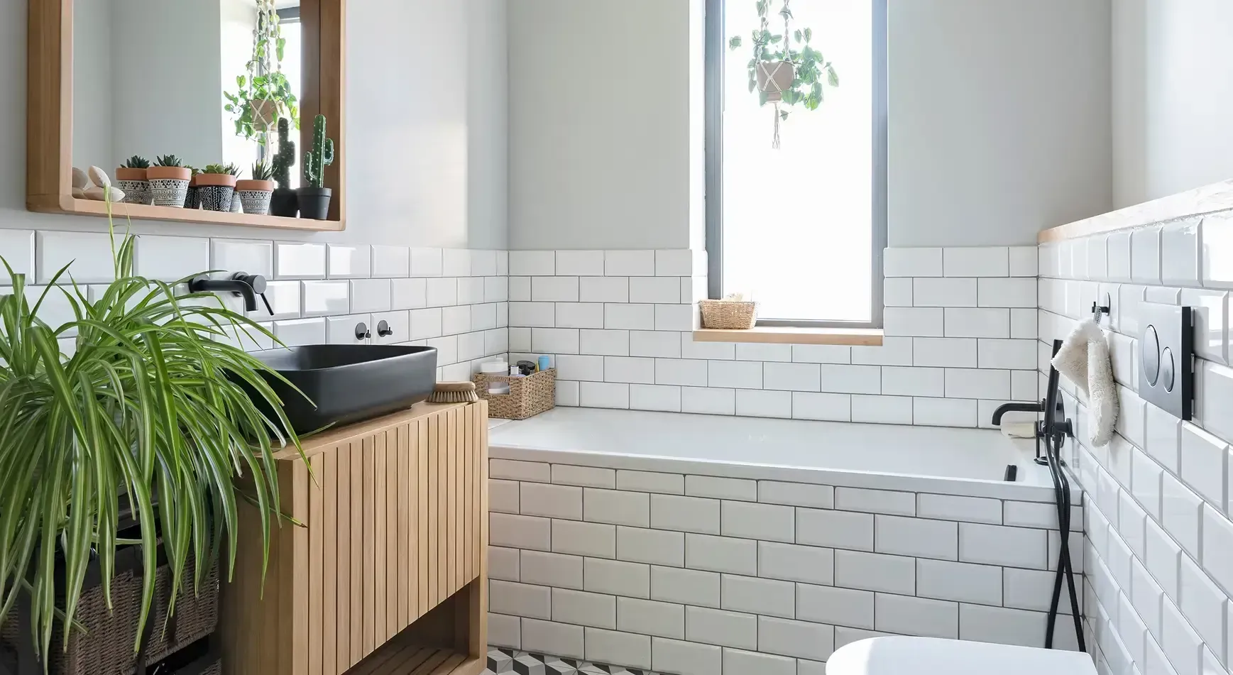 Bright bathroom with white tile walls, wood vanity, and a large green plant by the sink.
