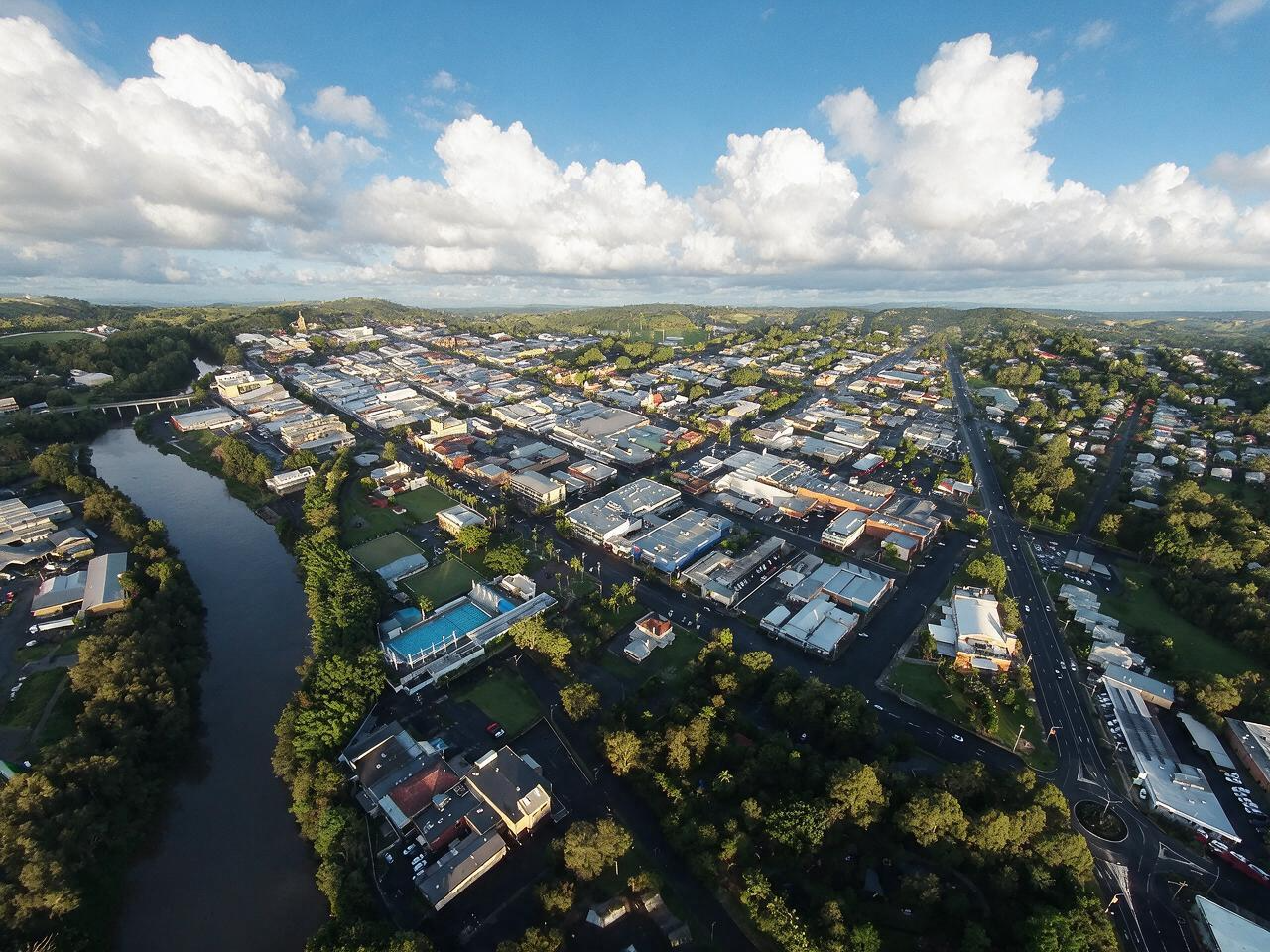 Aerial view of a suburban neighborhood beside a winding river under a cloudy blue sky