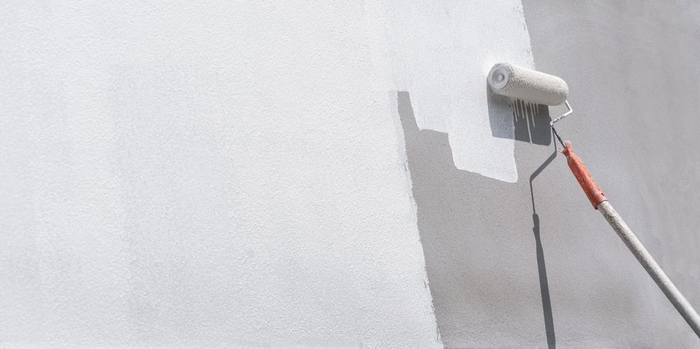 Paint roller applying white paint to a wall