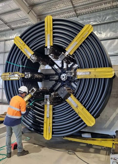 Elsam crew member winding a coil of poly pipe at the Livingstone plant