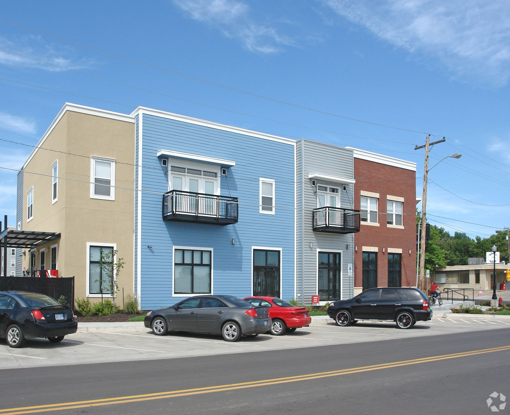 Multi-colored modern townhouses with parked cars on a sunny day.