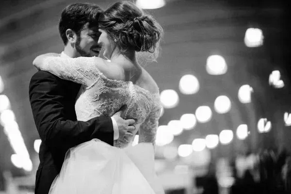 A black and white photo of a bride and groom dancing at their wedding reception.
