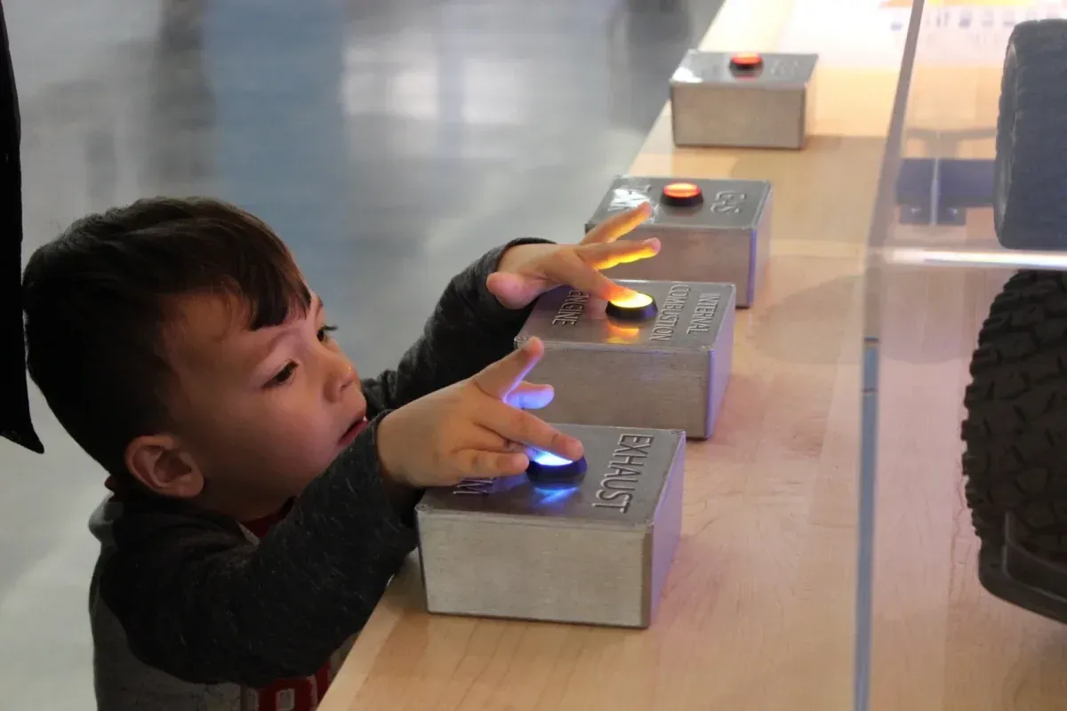 A young boy is playing with buttons on a table.