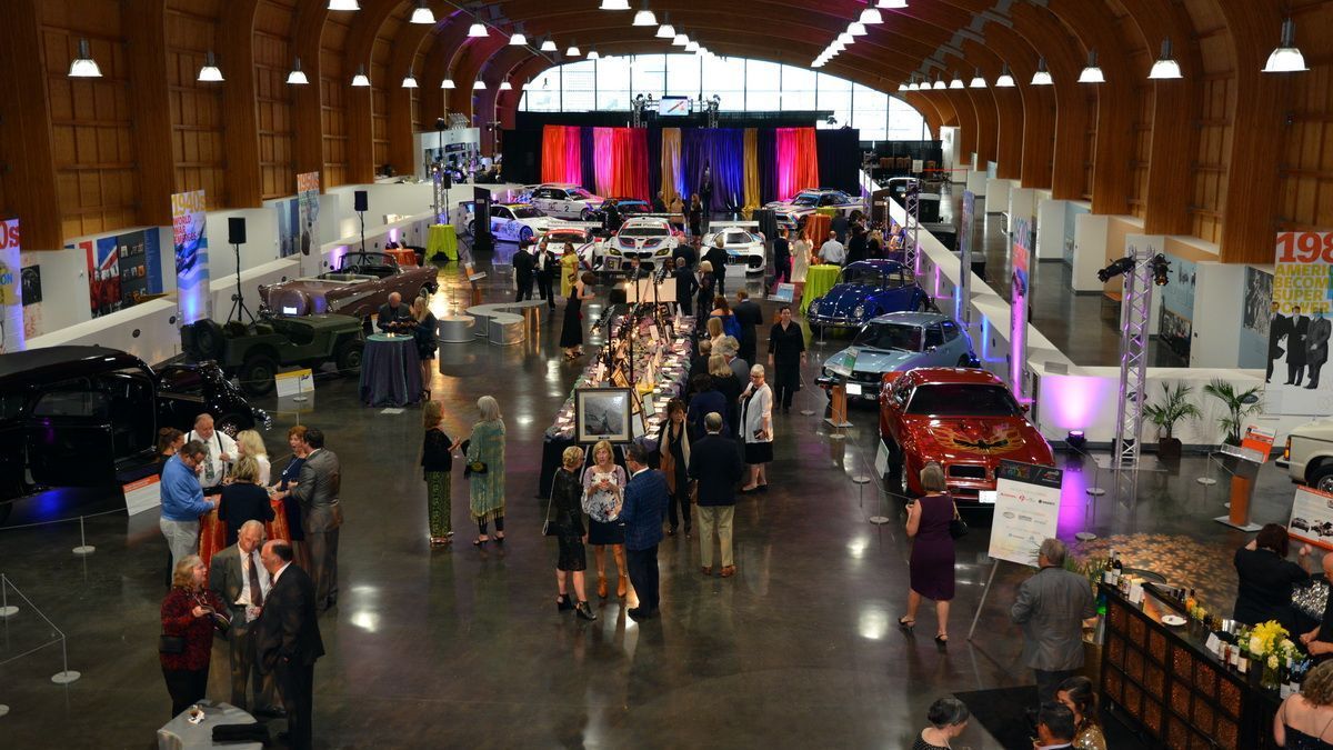 An aerial view of a large convention center filled with people and cars.