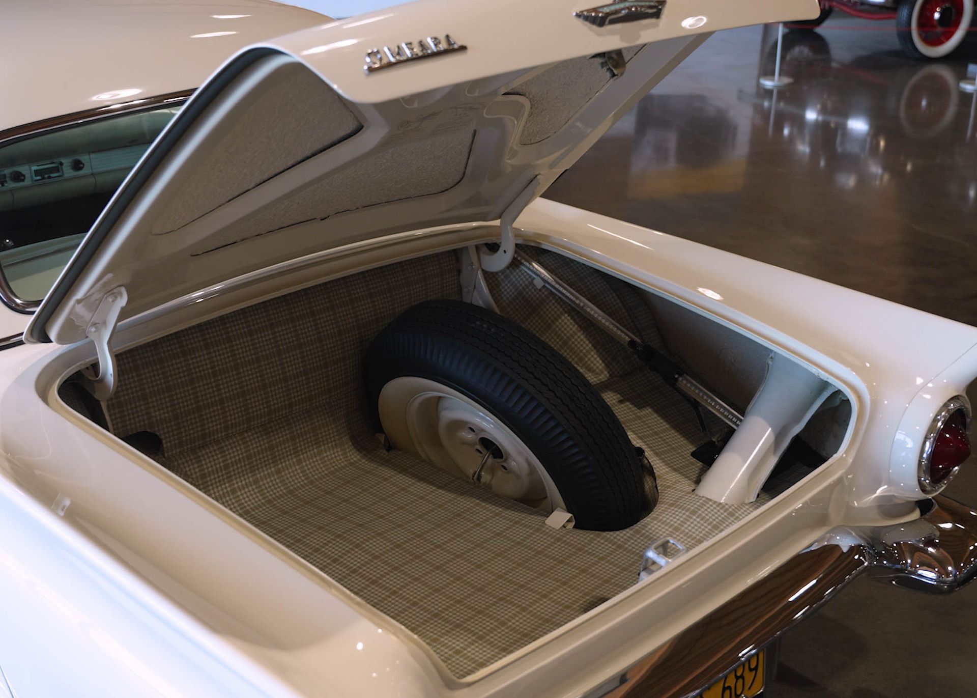 The trunk of a white car with a spare tire in it