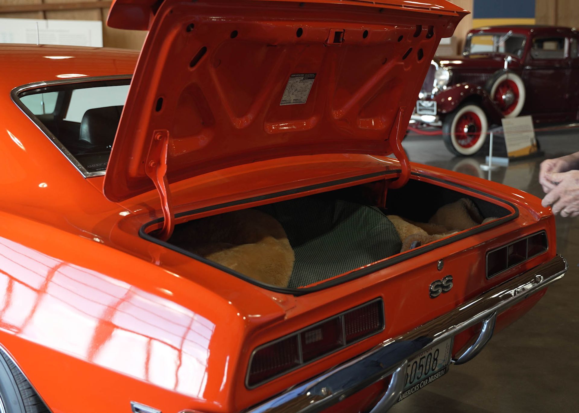 The trunk of an orange car with the hood open