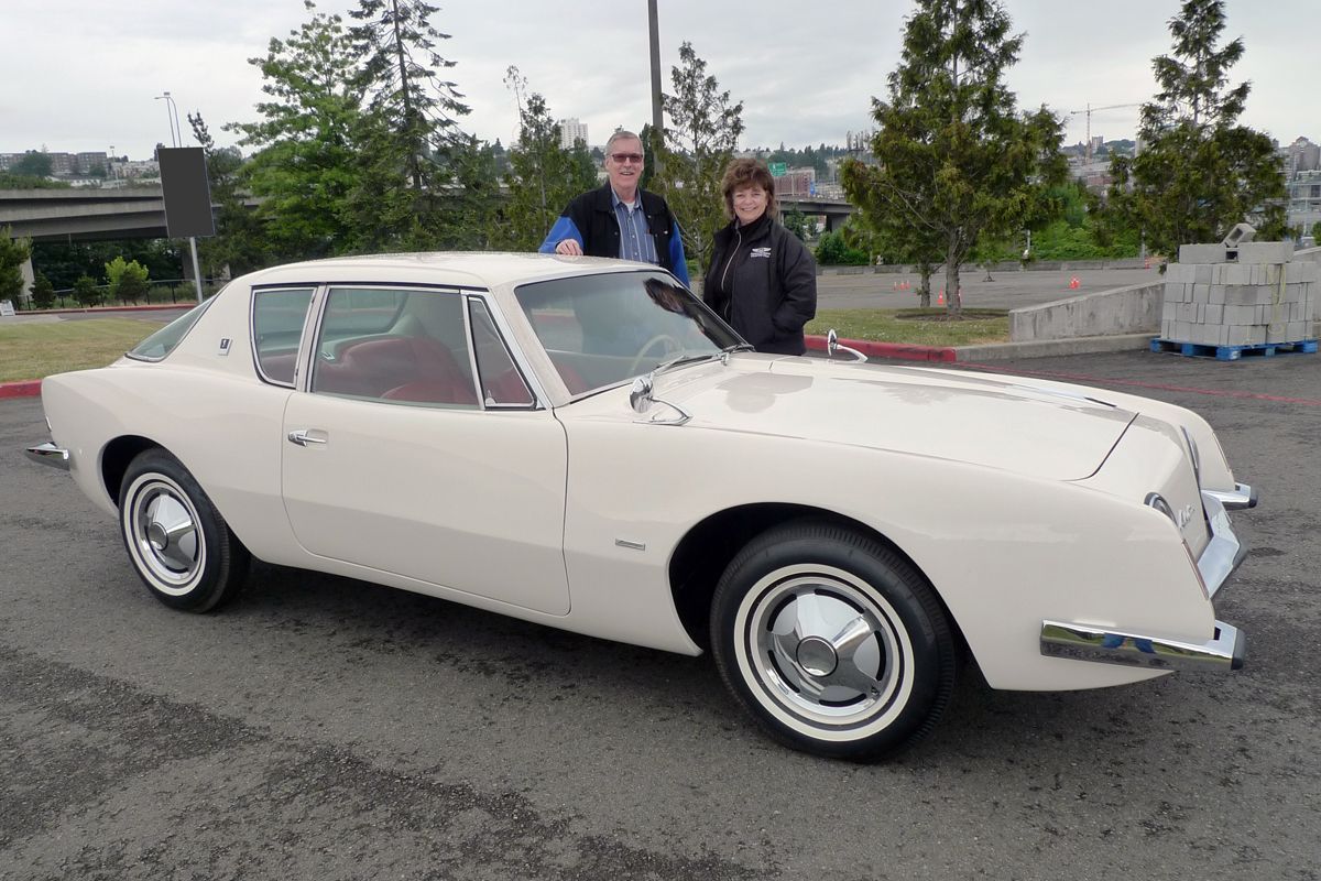 Two people standing next to a white car in a parking lot