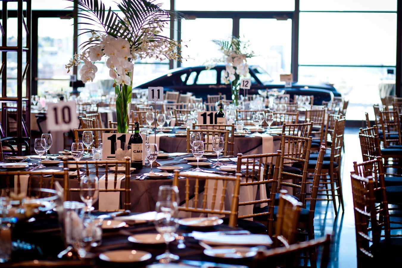 A banquet hall filled with tables and chairs and a car parked in the background.
