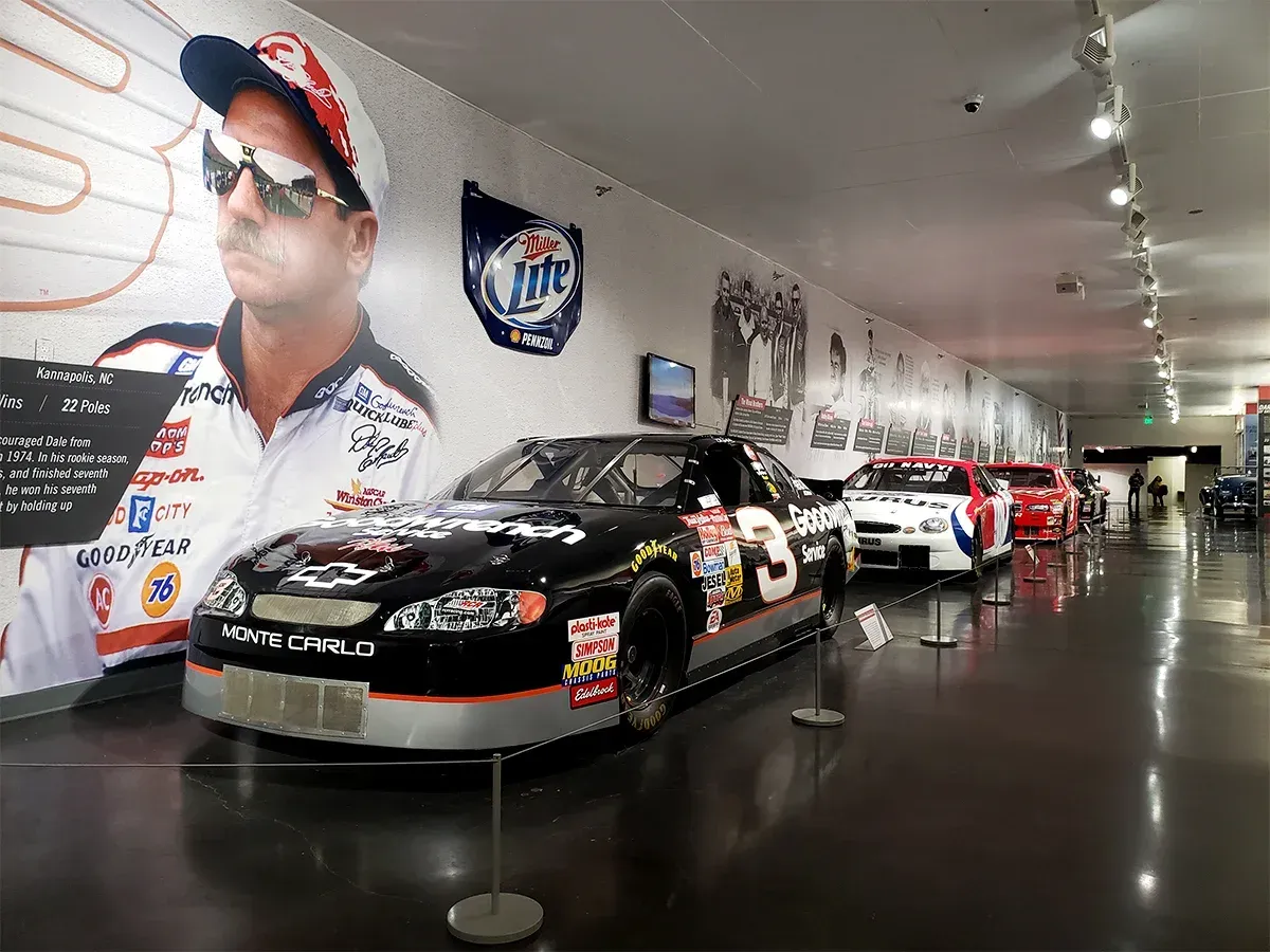 A row of cars and motorcycles are on display in a museum
