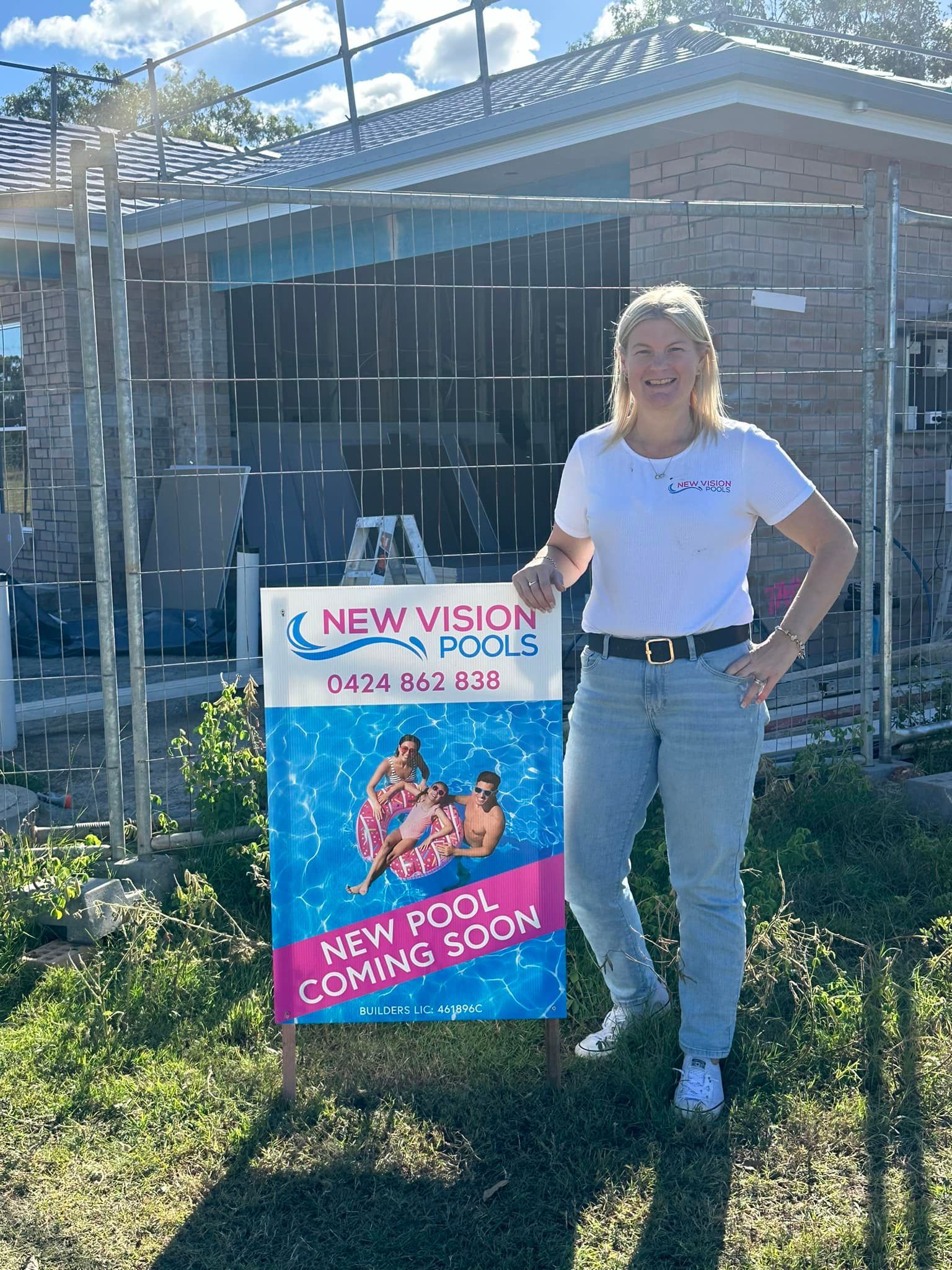 Woman Standing by A New Vision Pool Sign in Front of A Brick House and Fenced Yard — New Vision Pools in Port Macquarie, NSW