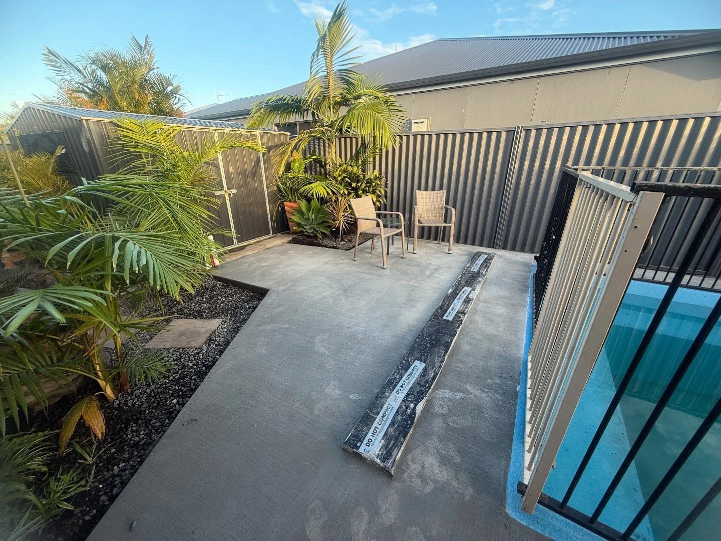 Backyard Patio with Concrete Seating Area and A Fenced Pool on The Right — New Vision Pools in Lake Cathie, NSW