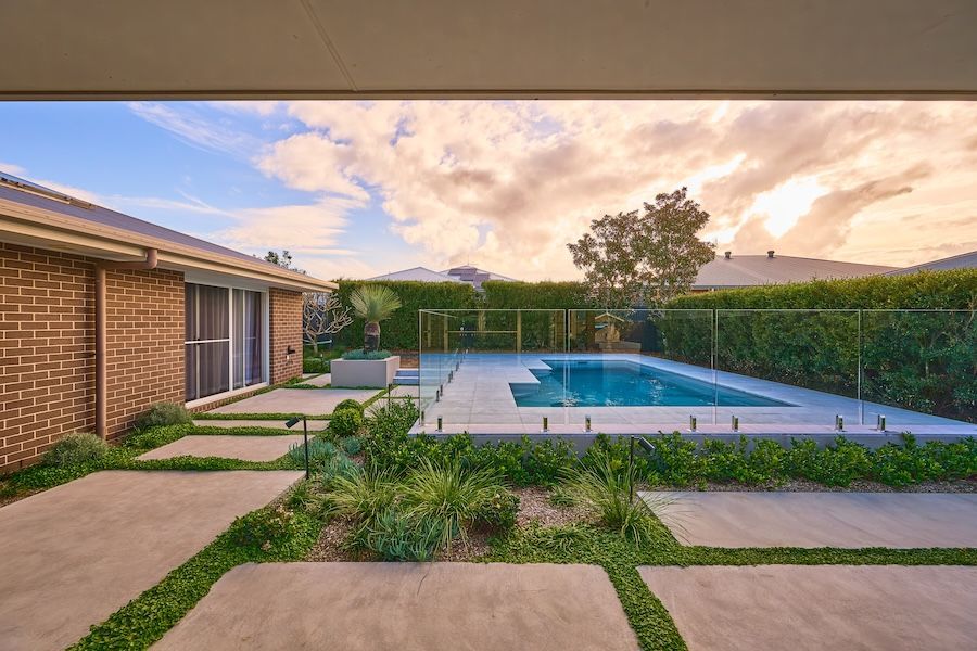 A Swimming Pool, Brick House, and Landscaped Garden at Sunset — New Vision Pools in Port Macquarie, NSW