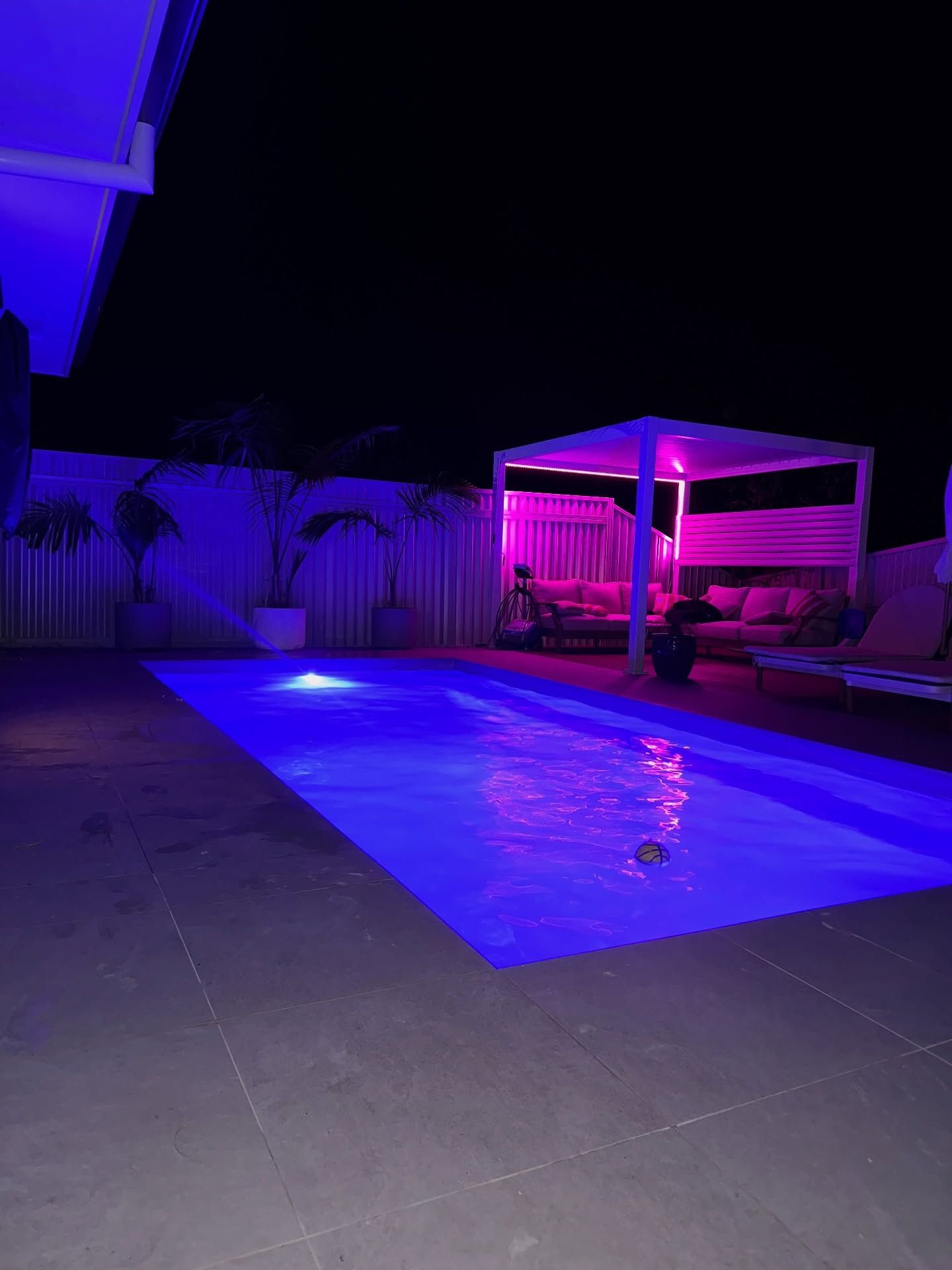 Purple Lit Backyard Pool at Night Beside a Cabana and Fence — New Vision Pools in Kempsey, NSW