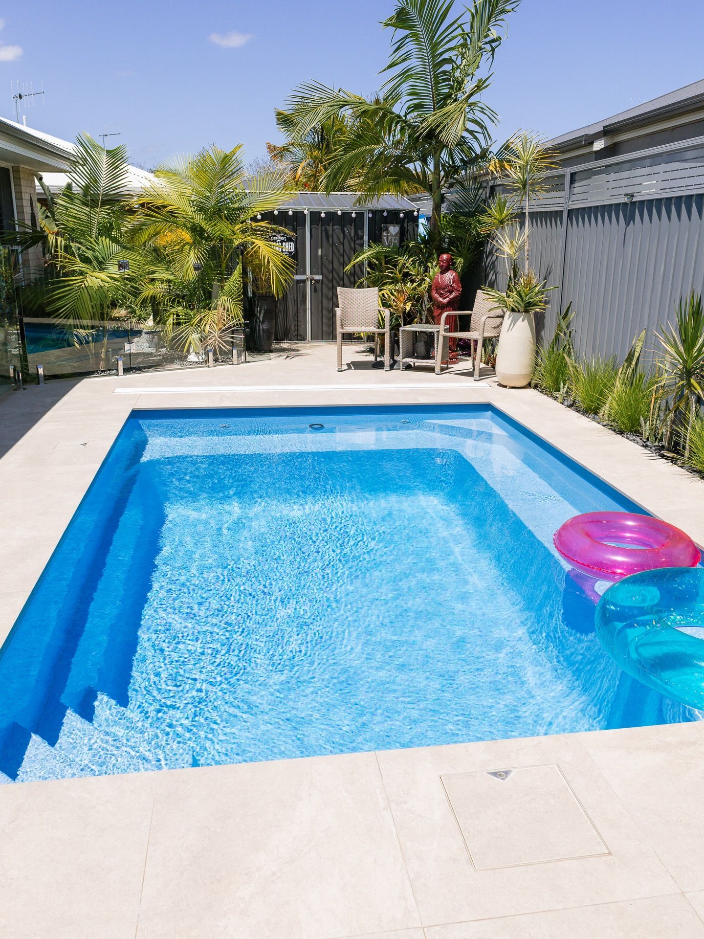 Backyard Pool with Blue Water, Pink Float, and Potted Plants Beside a Patio Seating Area — New Vision Pools in Port Macquarie, NSW