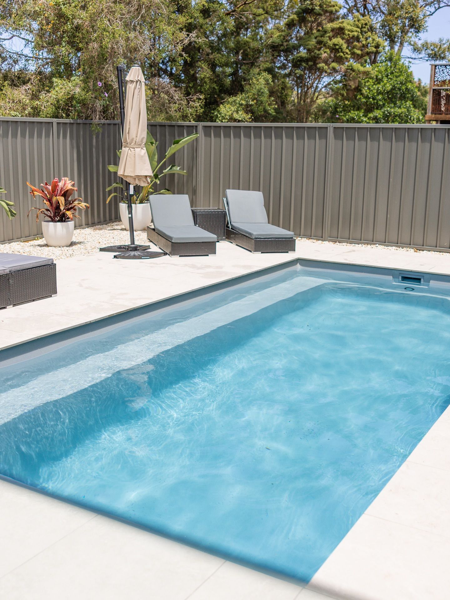 Backyard Swimming Pool with Two Lounge Chairs and Potted Plants — New Vision Pools in Port Macquarie, NSW