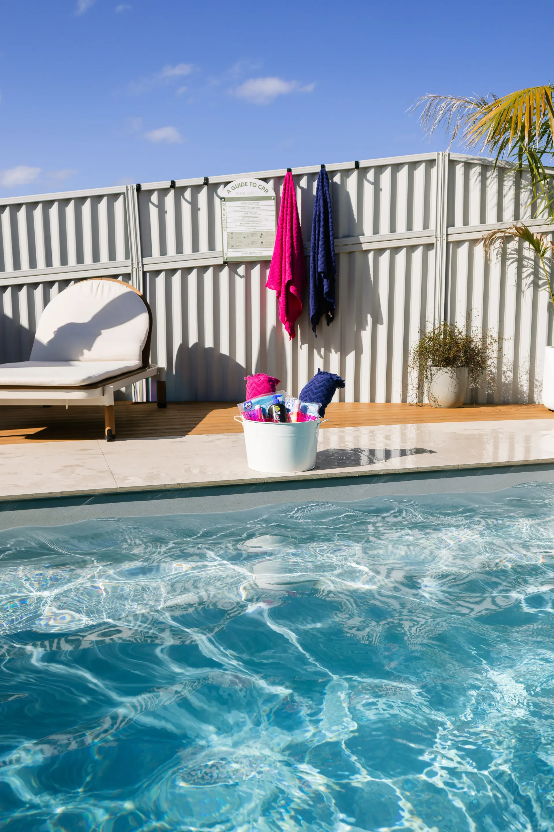 Poolside Lounge Chair, and Towels on A Fence Beside a Bright Blue Swimming Pool — New Vision Pools in Port Macquarie, NSW
